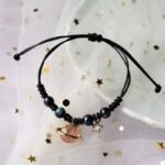 bracelet fantaisie planete avec anneau dore et perles colorees corde noire et planete rose 800 1