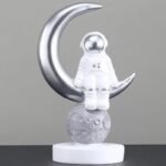 figurine astronaute assis sur croissant de lune en resine argentee 985 1